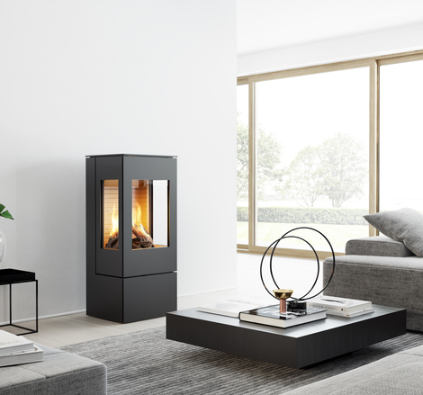 NEXO 100 GAZ en noir avec deux vitres latérales Poêle à gaz NEXO 100 en noir avec porte en acier et deux vitres latérales dans un salon moderne et lumineux