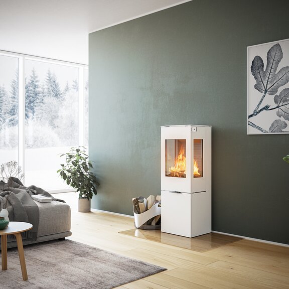 Stufa a legna NEXO 120 in bianco con porta in acciaio e due finestre laterali davanti a una parete verde in un soggiorno decorativo