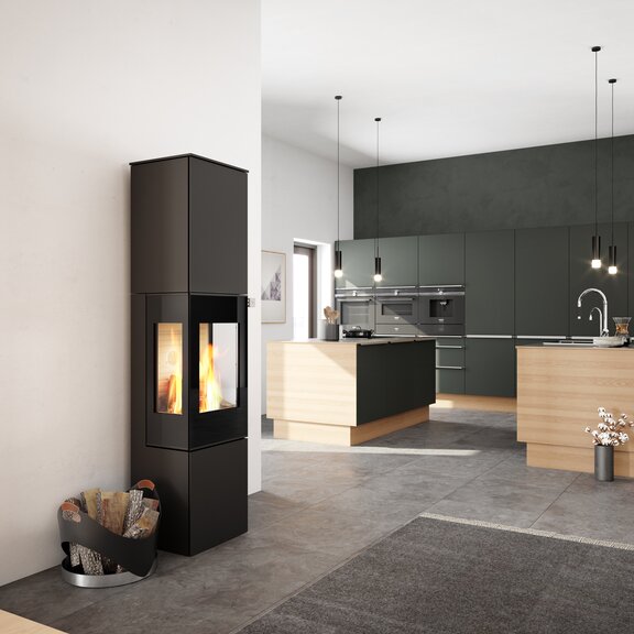 Stufa a legna NEXO 185 in nero con porta del focolare in vetro e due finestre laterali al centro della cucina e del soggiorno