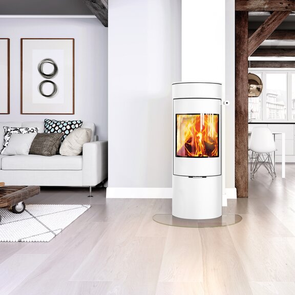 Stufa a legna VIVA 120 L in bianco con porta in acciaio in un luminoso appartamento open space