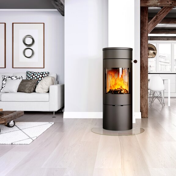 Stufa a legna VIVA 120 L in nero con porta in acciaio in un luminoso appartamento open space