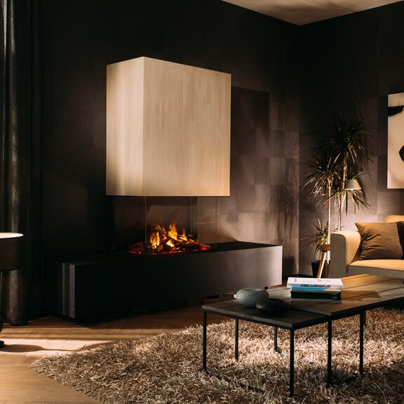 Foyer électrique eMatriX Mood 800/500 tri-face vitrée dans un salon élégant avec des murs sombres et des meubles clairs.