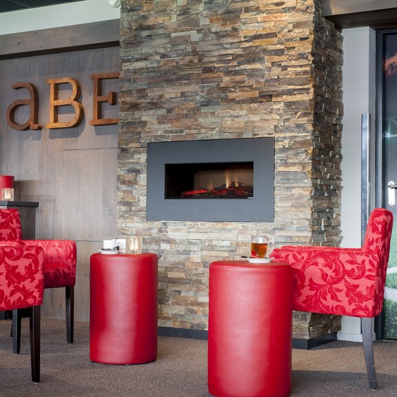 Feu d'effet électrique Opti-V-Single dans le bar avec des meubles rouges encastrés dans un mur en pierre