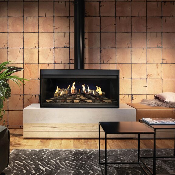 Le foyer indépendant E-One 100 Front dans le salon avec un style industriel devant un mur de pierres de ruisseau.