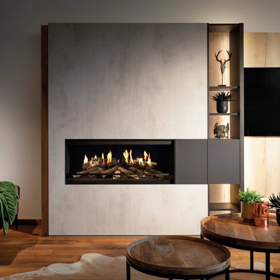 Le foyer électrique E-One 100 face dans le salon encastré dans un élément en béton.
