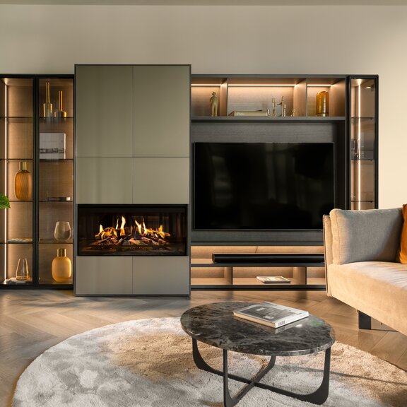 Cheminée électrique E-One 100 F intégrée dans un meuble mural moderne avec étagère et TV dans un salon sobre avec canapé dans les tons bruns