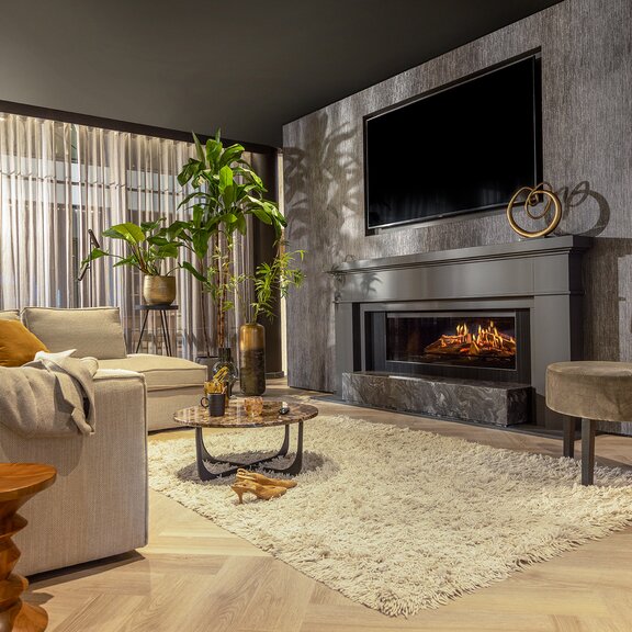 Le foyer électrique E-One 130 Face encastré sur le mur noir dans un salon confortable au style hygge.