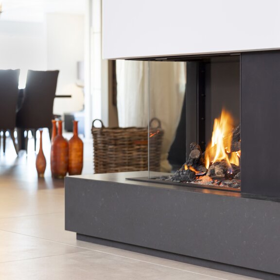 Corner version gas fireplace GP65/55C on a black base unit in the dining room with chandelier