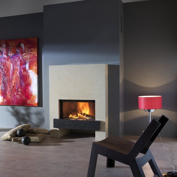 Camino a legna W70/33F di Kalfire con rivestimento in pietra naturale color crema davanti a una parete grigia con decorazione rosa